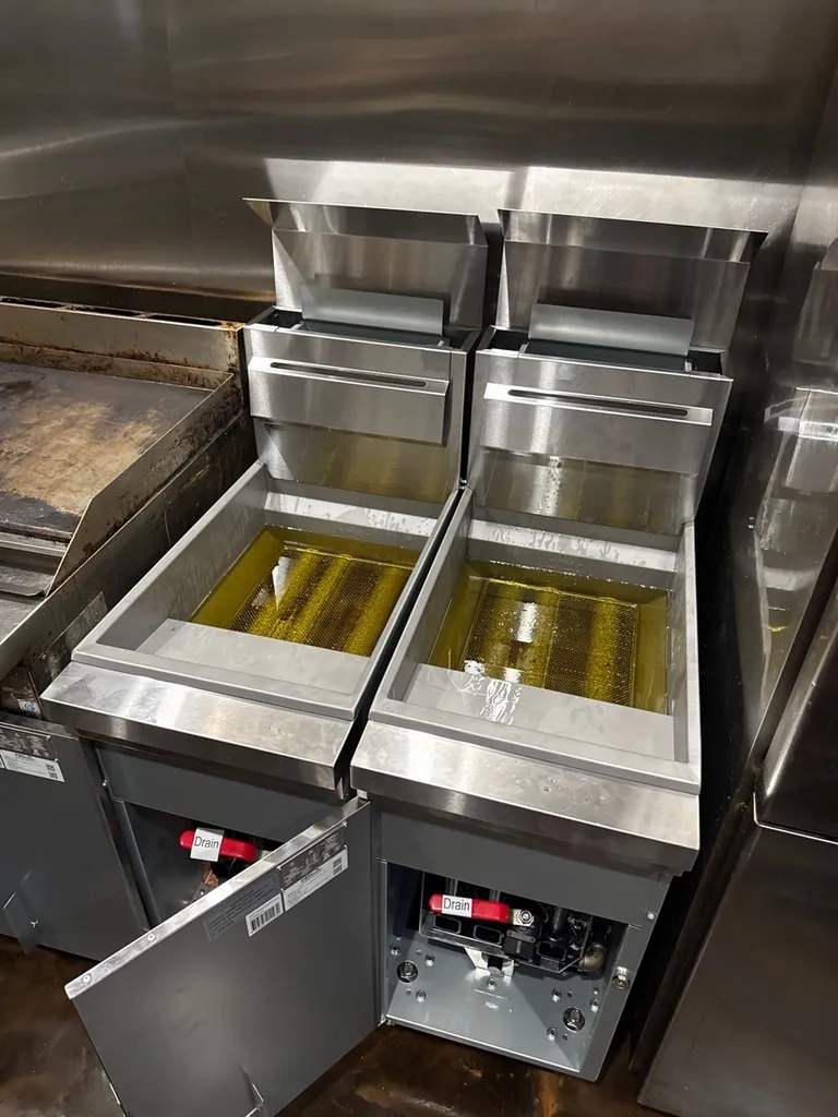 Pair of stainless steel commercial gas deep fryers in a restaurant kitchen