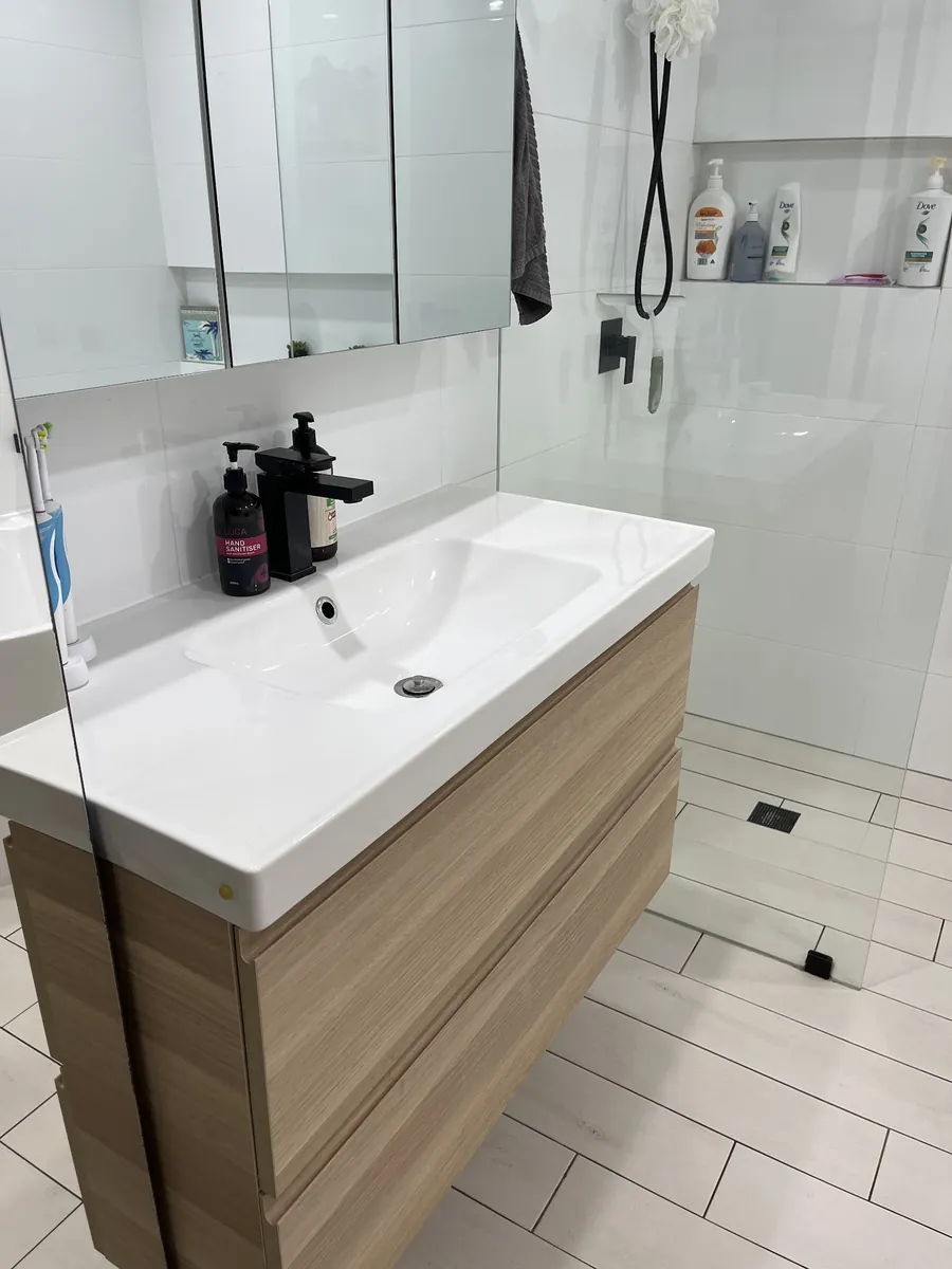 Timber-look wall-hung vanity next to a frameless shower